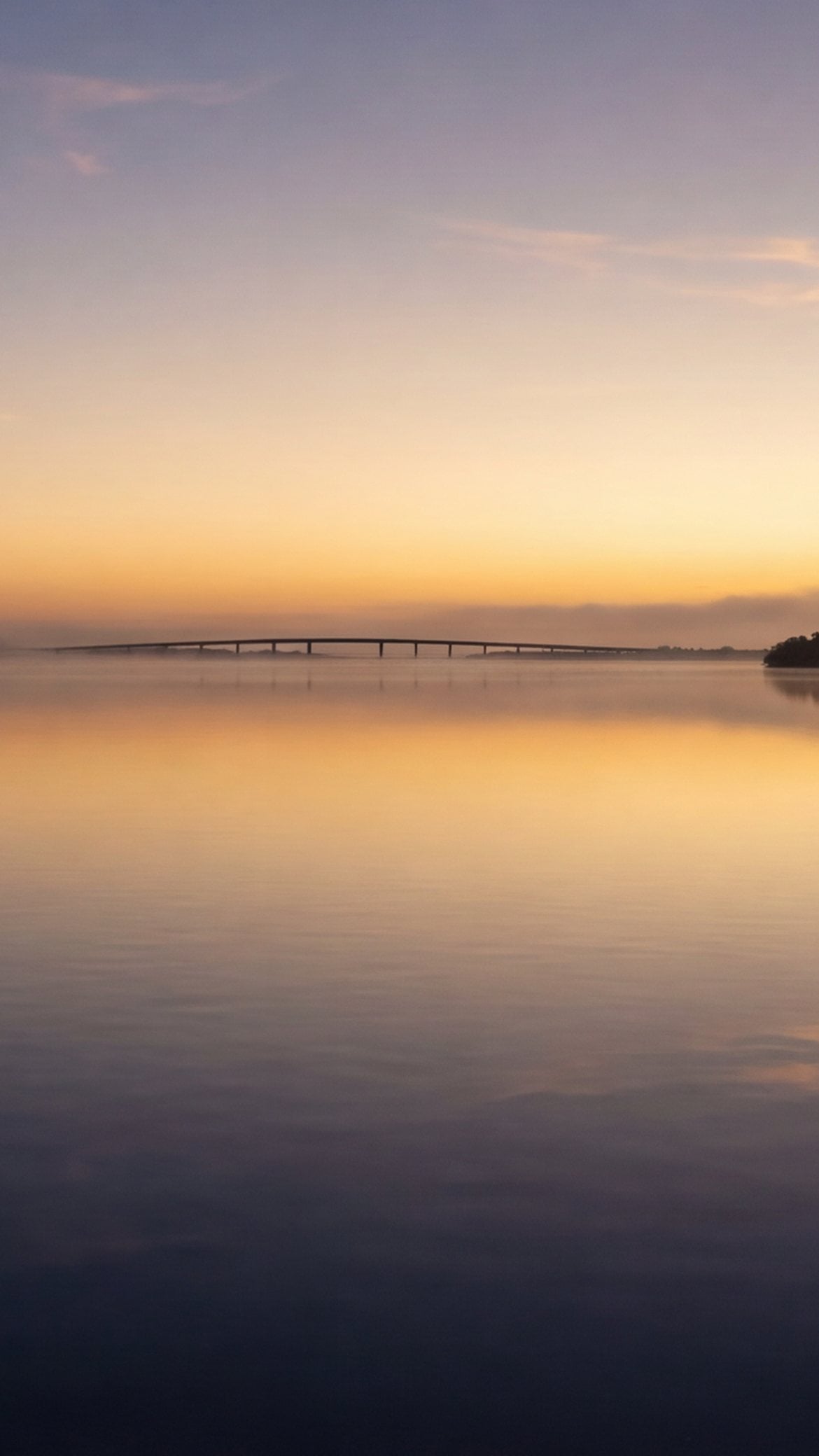 Calm lagoon water and a distant causeway at first light