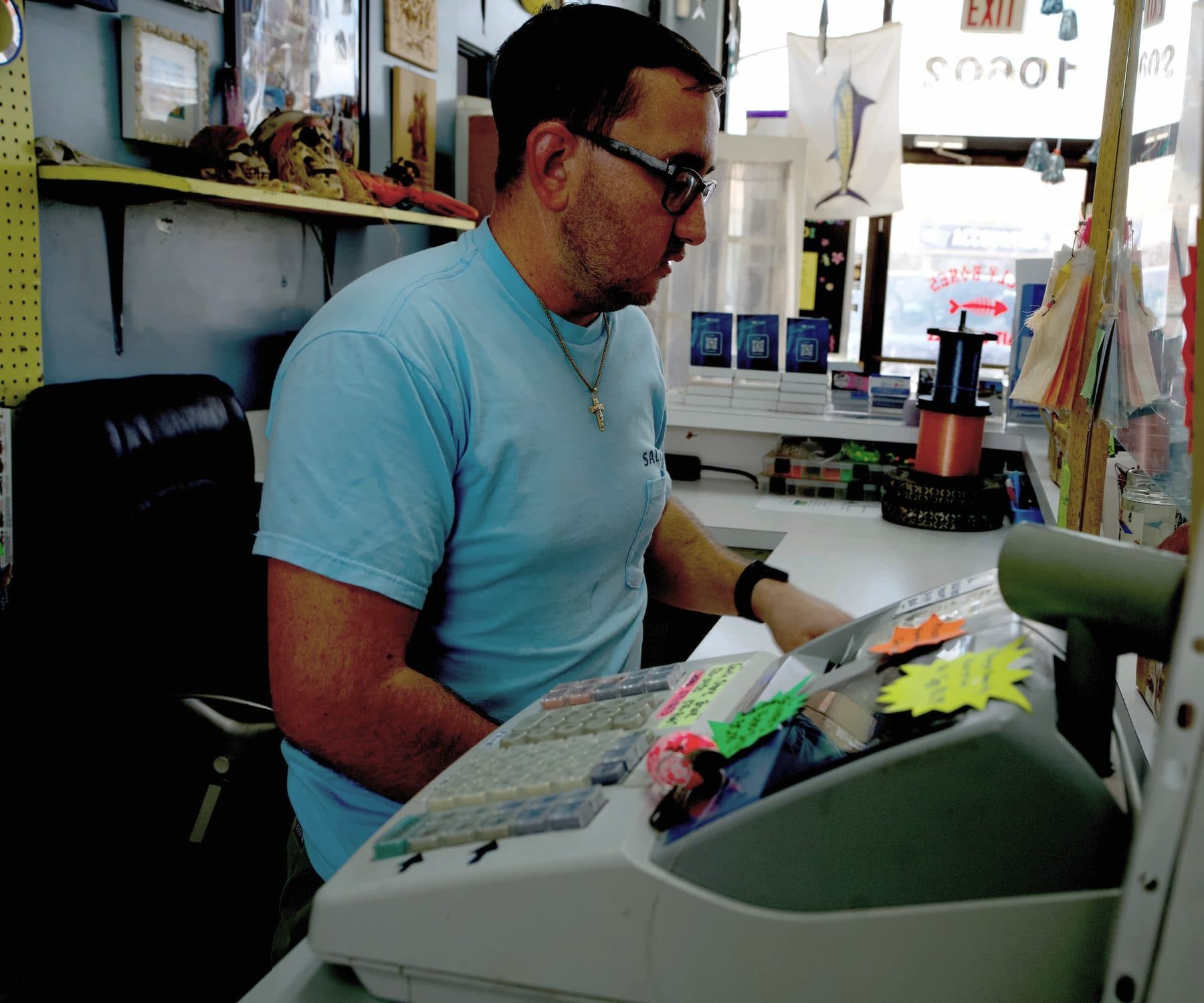 Crew member in a light blue shirt working the cash register at the front counter, bright windows behind