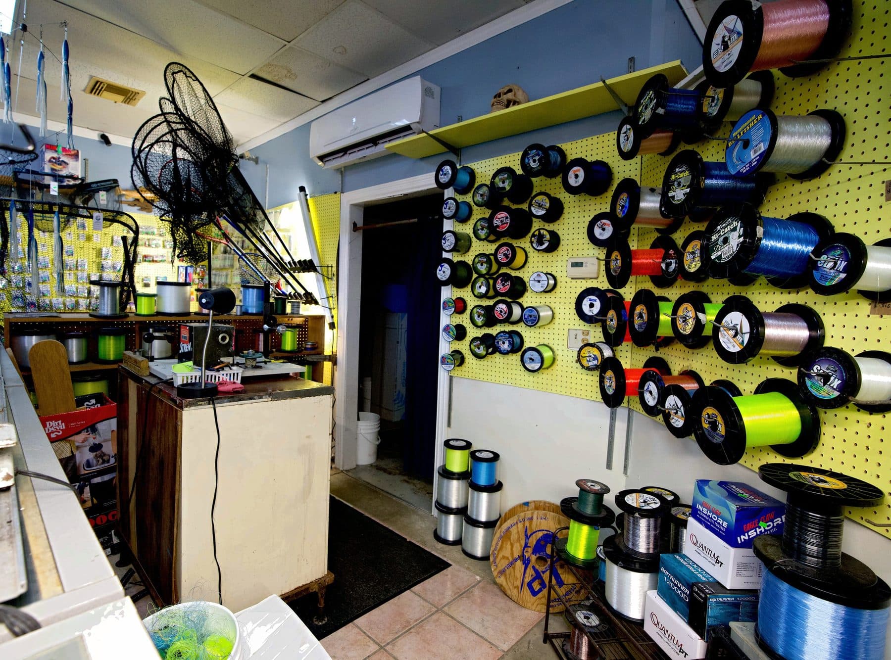 Back tackle room with a yellow pegboard wall of bulk Sufix, Momoi and Billfisher line spools beside a spooling counter
