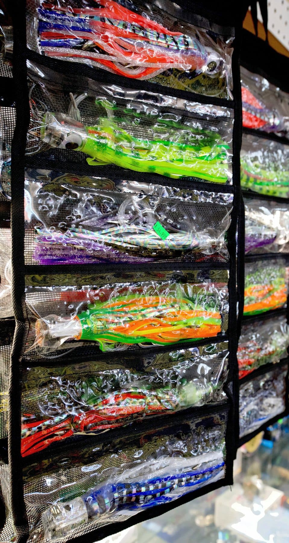 Hanging mesh lure bag with clear pockets of rigged trolling skirts in orange, green, purple, red and blue