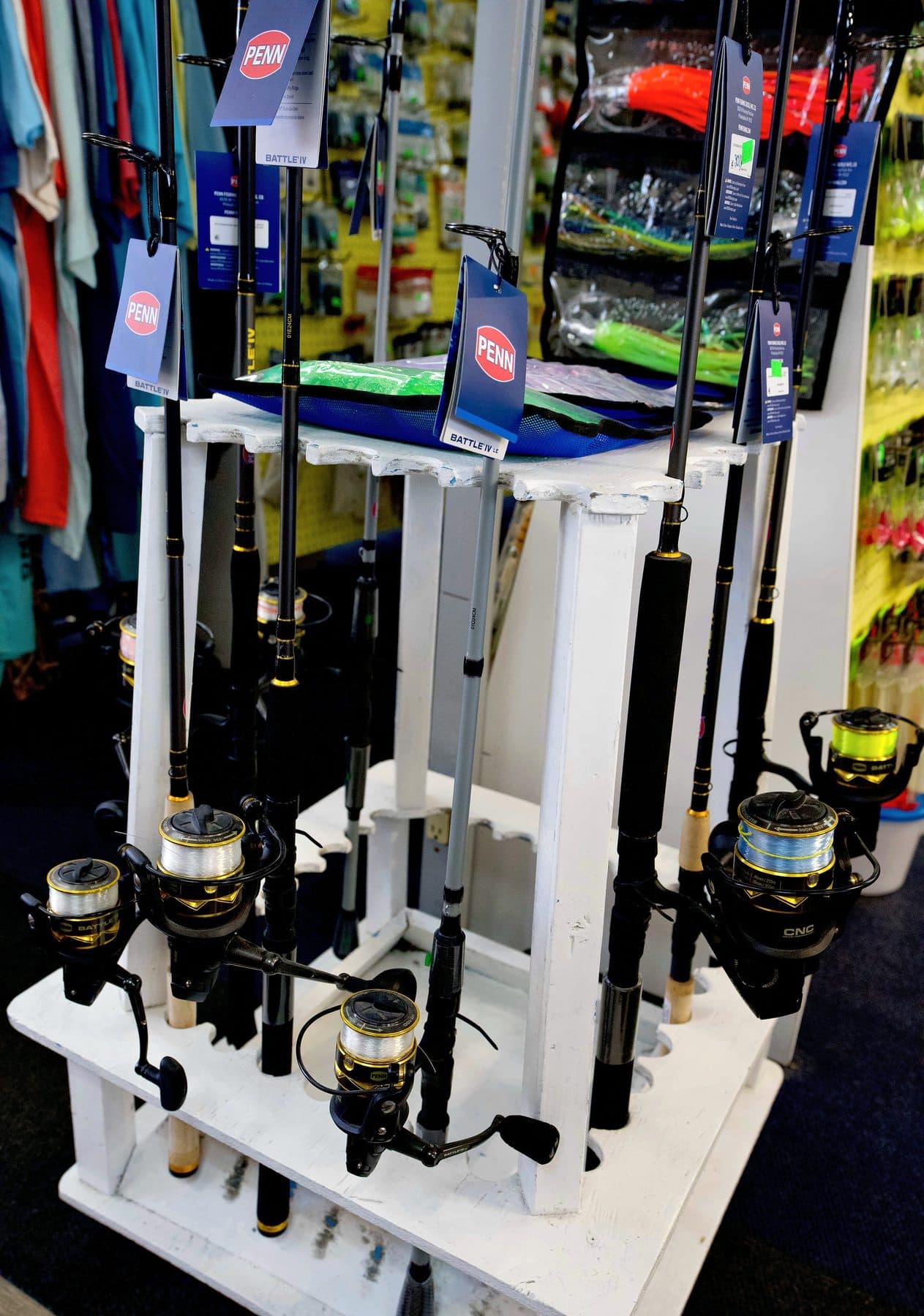 White wooden floor rack of PENN Battle IV spinning rods with black and gold PENN Battle reels spooled with line