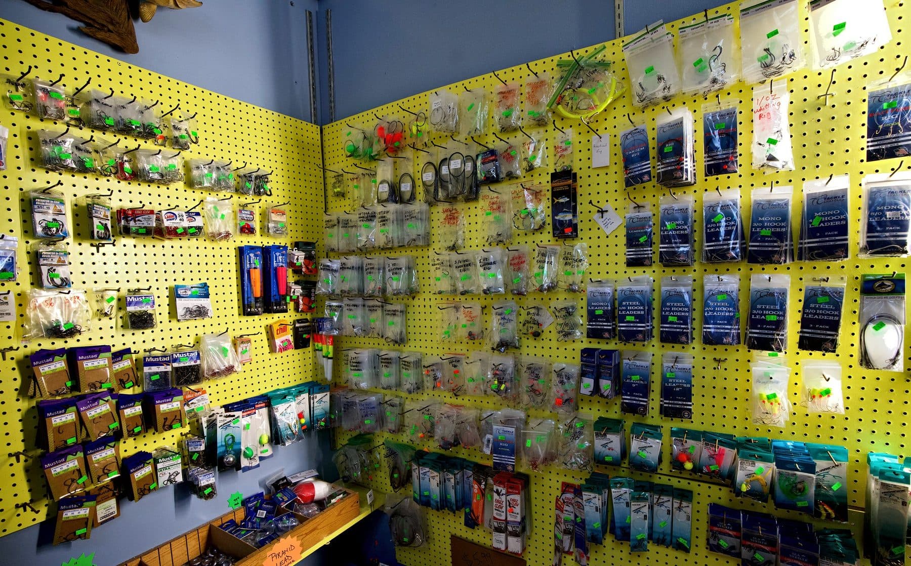 Yellow pegboard corner stocked with Mustad hooks, Tackle Crafters leaders, bagged rigs and bins of lead sinkers