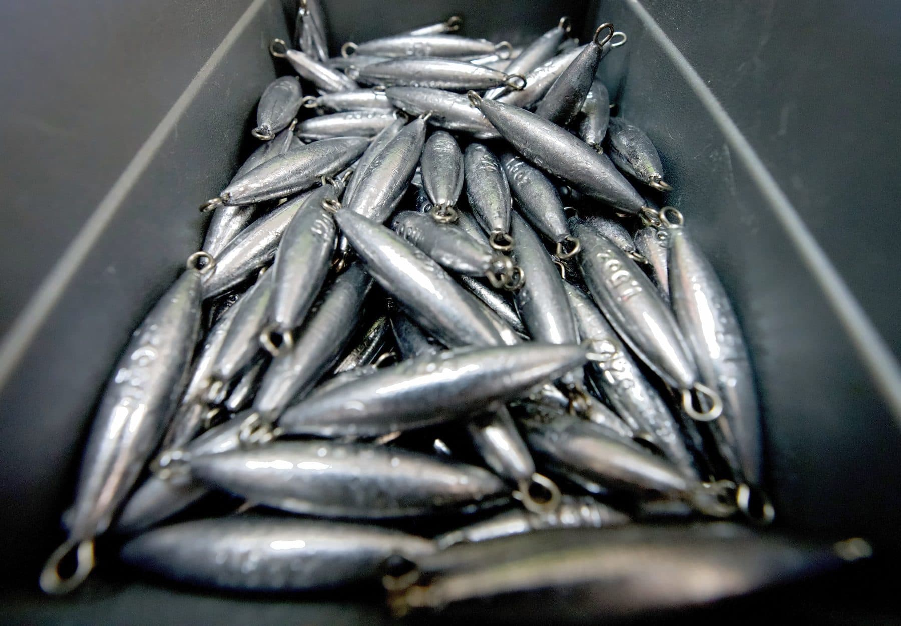 Close view of a black bin filled with torpedo lead sinkers with twisted wire eyes